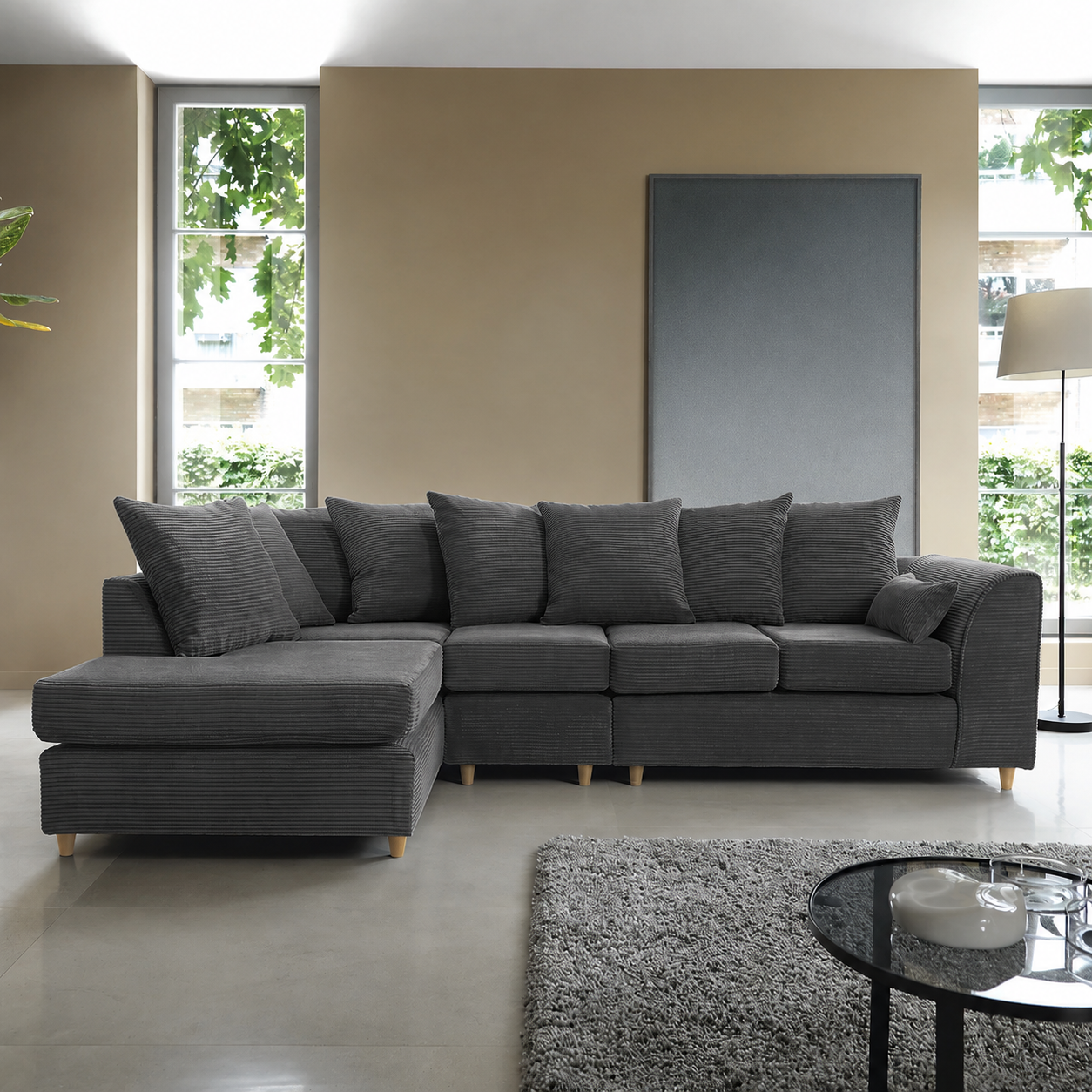 Dark grey jumbo cord corner sofa in a modern living room with minimalist decor and large windows